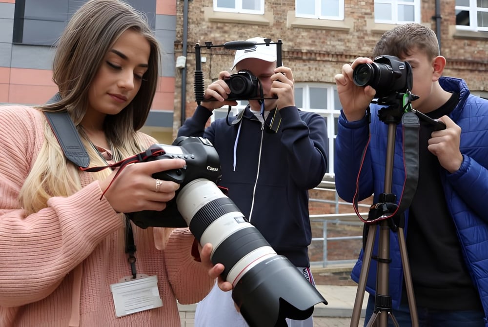 Eine Gruppe von Schülern der Ringwood School fotografiert mit Kameras vor Backsteingebäuden in der Stadt.