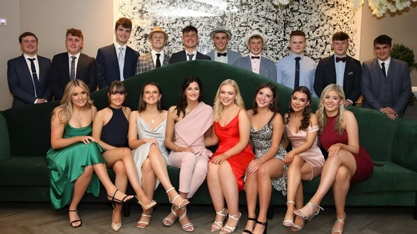 Eine Gruppe von Personen in formeller Kleidung posiert vor einem floralen Hintergrund auf dem Campus der Rishworth School.