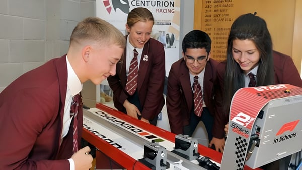 Schüler der Rishworth School in Schuluniformen versammeln sich um einen Rennsimulator und nehmen an einer Aktivität teil.