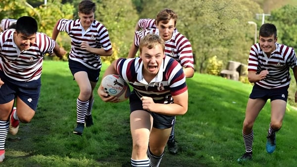 Eine Gruppe von Schülern der Rishworth School spielt ein intensives Rugby-Spiel auf einem grasbewachsenen Spielfeld.