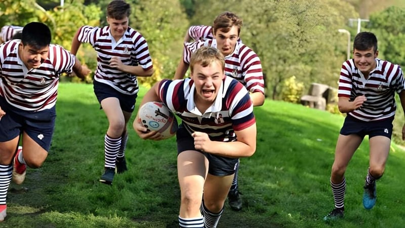 Eine Gruppe von Schülern der Rishworth School spielt ein intensives Rugby-Spiel auf einem grasbewachsenen Spielfeld.