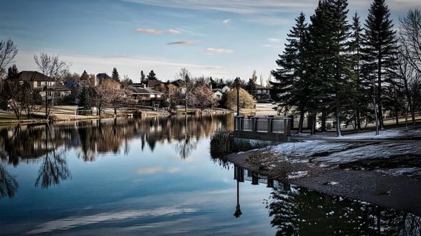 Eine ruhige Winterlandschaft mit einem See und Kiefern vor Gebäuden auf dem Gelände des River East Collegiate.