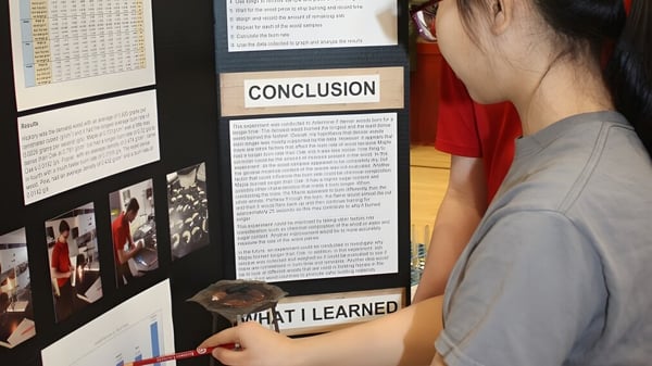 Eine Person präsentiert ein Projekt auf einem Plakat vor Schülern am Rivermont Collegiate.