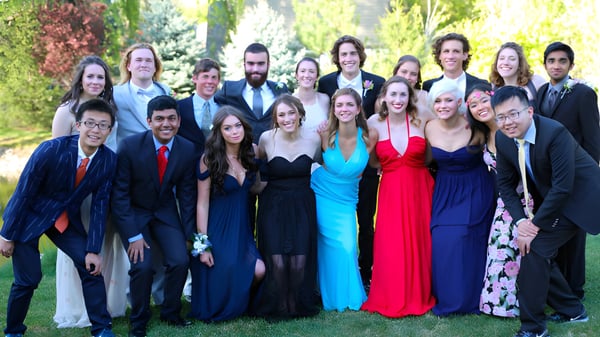 Eine Gruppe von Personen in formeller Kleidung posiert gemeinsam draußen auf dem Campus der Riverstone International School.