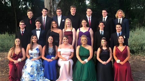 Eine Gruppe von Personen in formeller Kleidung steht gemeinsam im Freien auf dem Gelände der Riverton and District High School.