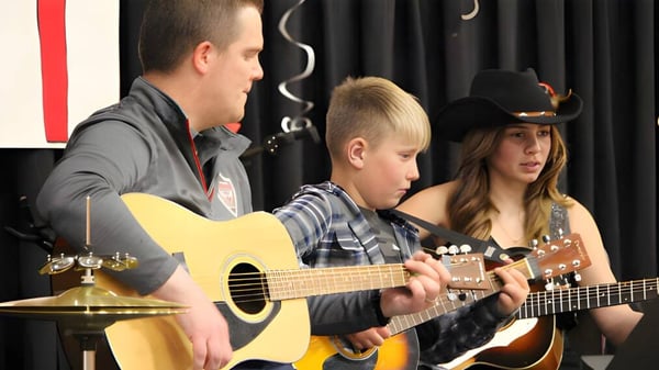 Drei Schülerinnen und Schüler der Riverview Middle School spielen gemeinsam Instrumente in einem Musikzimmer.