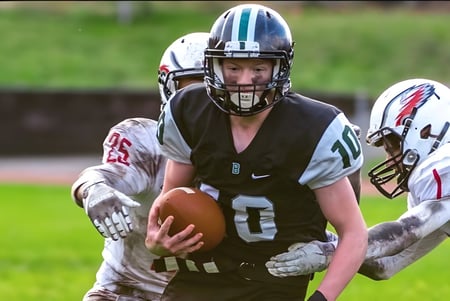 Ein Footballspieler in schwarzem Trikot läuft mit dem Ball auf dem Spielfeld der Robert Bateman Secondary School.