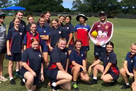 Eine Gruppe junger Athletinnen der Rochedale State High School posiert gemeinsam auf einem Grasfeld.