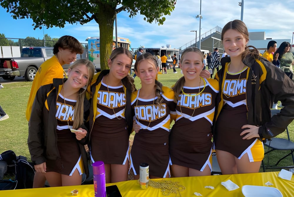 Eine Gruppe junger Cheerleaderinnen posiert auf einem Rasenfeld auf dem Campus der Rochester Community Schools.