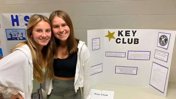 Zwei Schülerinnen stehen vor dem Key Club Infobrett auf dem Campus der Rochester Community Schools.
