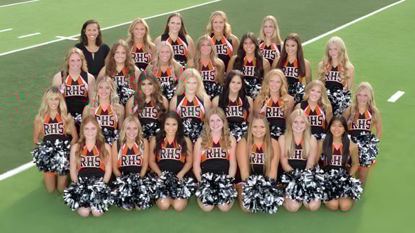 Cheerleader der Rockford High School posieren in einheitlichen Uniformen auf einem grünen Sportfeld.