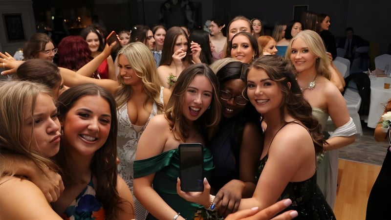 Eine Gruppe junger Frauen posiert für ein Gruppenfoto auf dem Campus der Rockford Manor School, eine Frau hält ein Smartphone.