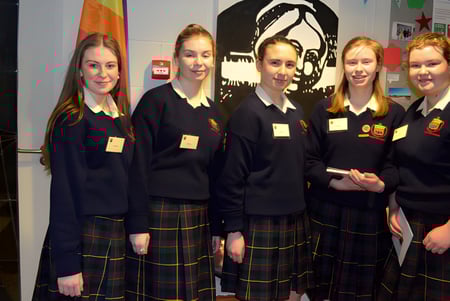 Fünf Schülerinnen in Schuluniformen stehen vor einem bunten Wandgemälde auf dem Campus der Rockford Manor School.