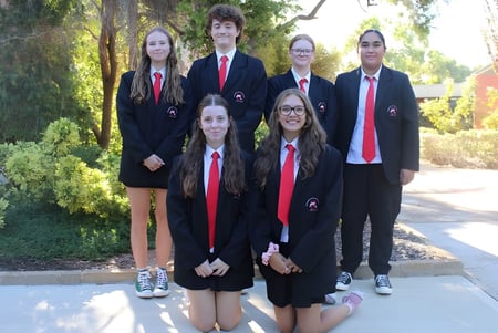 Eine Gruppe von sechs Schülern der Rockingham Senior High School steht in formeller Kleidung im grünen Außenbereich der Schule.