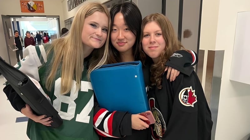 Drei Schülerinnen der Rockland District High School stehen im Flur zusammen und umarmen sich.