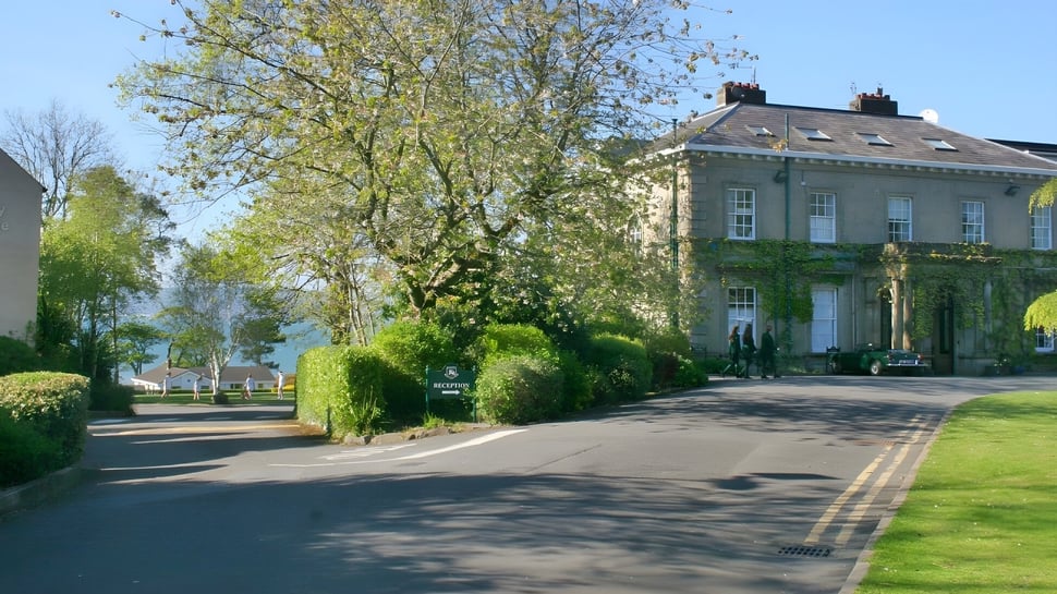 Das große efeubewachsene Gebäude auf dem Campus der Rockport School ist von grünen Bäumen und einem gewundenen Weg umgeben.