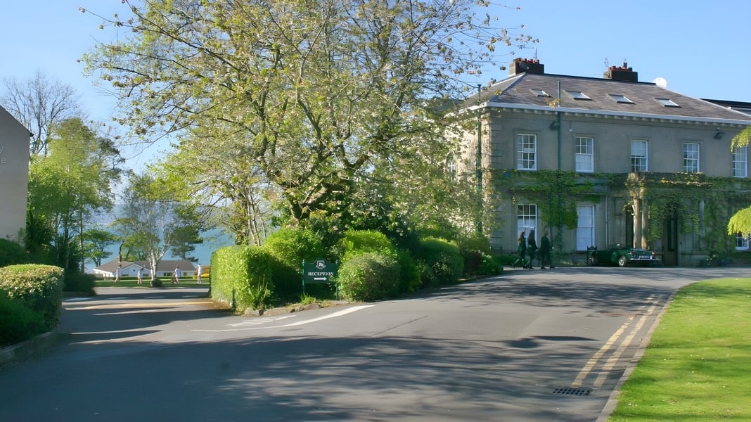 Das große efeubewachsene Gebäude auf dem Campus der Rockport School ist von grünen Bäumen und einem gewundenen Weg umgeben.