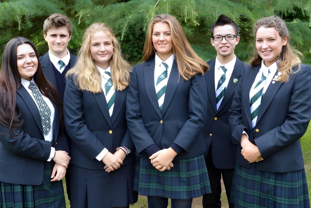 Eine Gruppe Schülerinnen und Schüler der Rockport School steht gemeinsam auf einer grasbewachsenen Fläche mit Bäumen im Hintergrund.
