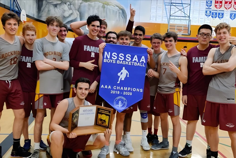 Eine Gruppe von Basketballspielern der Rockridge Secondary School hält stolz ein Meisterschaftsbanner in der Sporthalle.