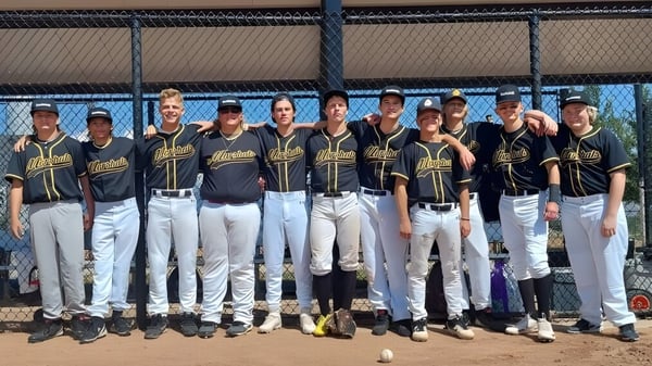 Eine Gruppe von Baseball spielenden Schülerinnen und Schülern steht auf dem Baseballfeld der Rockwell Charter School.
