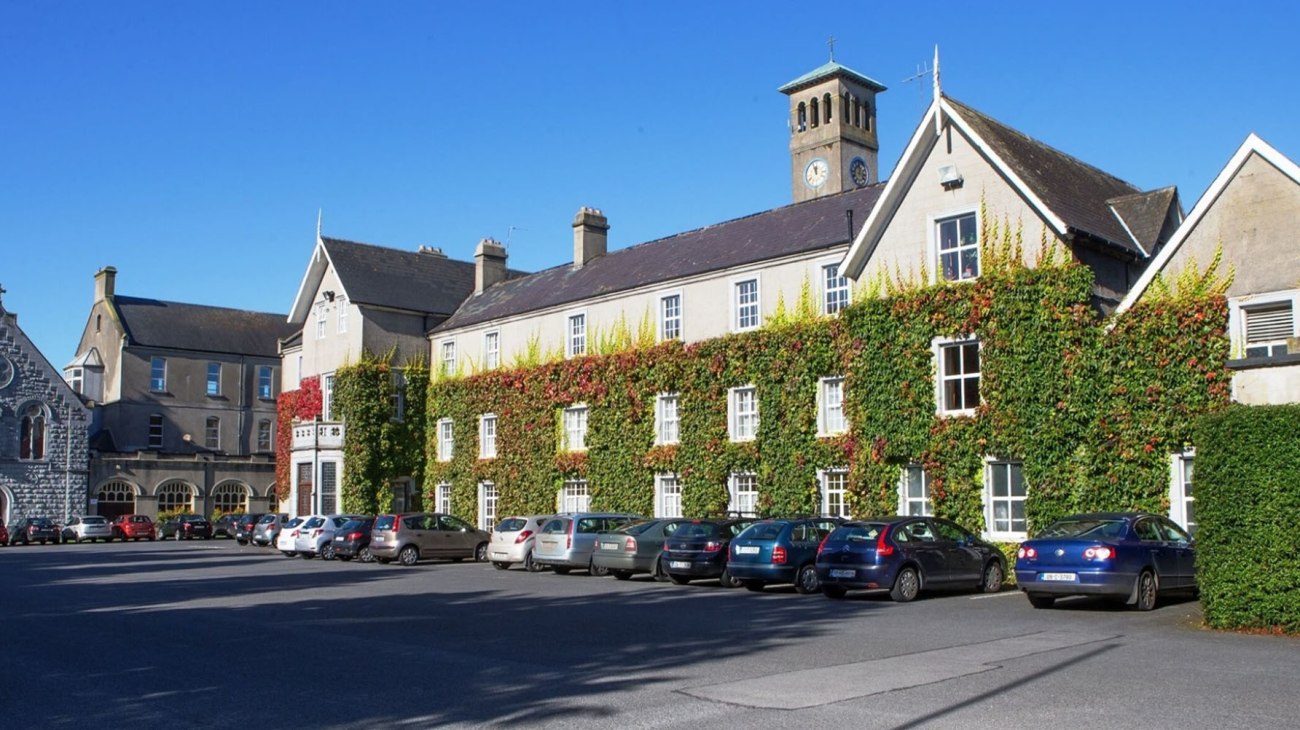 Ein historischer Ortsplatz mit alten Gebäuden und geparkten Autos nahe dem Rockwell College.