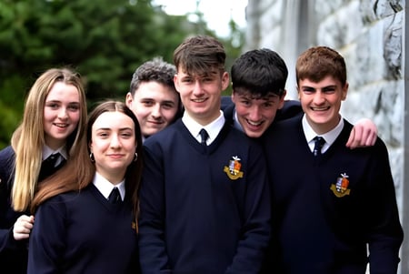 Eine Gruppe Schüler der Rockwell College steht zusammen vor einer Steinmauer mit Grünpflanzen.
