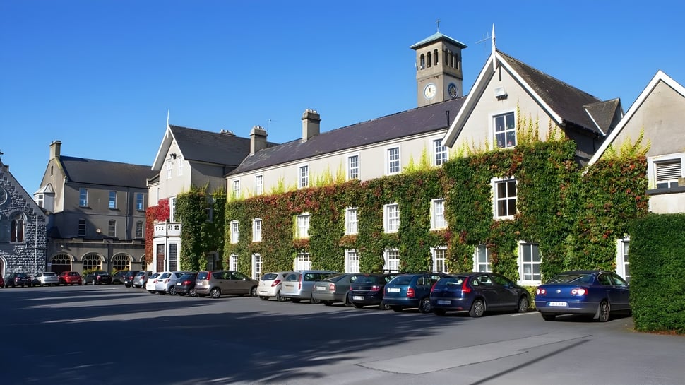 Der historische Stadtplatz mit einem hohen Glockenturm und efeubewachsenen Gebäuden vor dem Rockwell College.