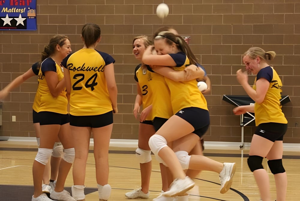 Eine Gruppe junger Volleyballspielerinnen der Rockwell Charter School feiert auf dem Basketballfeld.