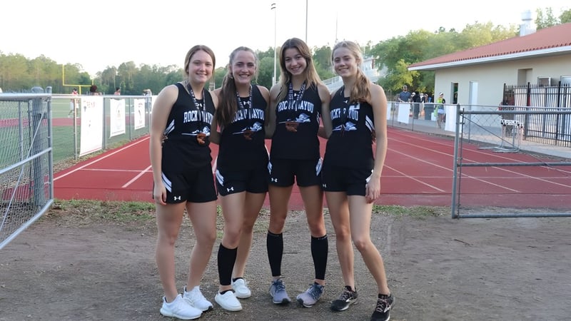 Vier Schülerinnen in Sportkleidung stehen gemeinsam auf dem Sportfeld der Rocky Bayou Christian High School.