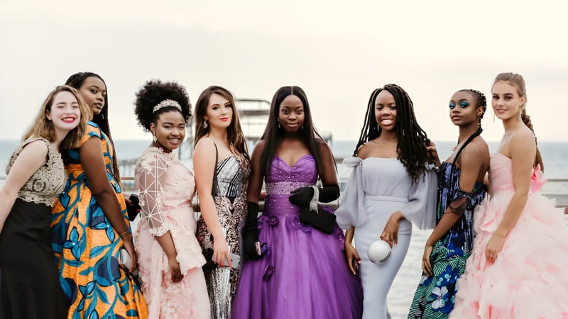 Eine Gruppe vielfältiger Frauen in eleganten Kleidern posiert gemeinsam vor weißem Hintergrund an der Roedean School.