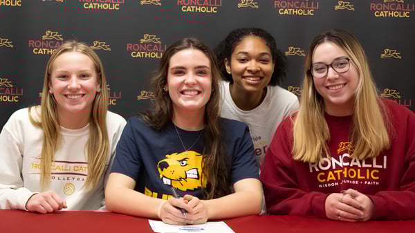 Vier Schülerinnen posieren gemeinsam vor einem Roncalli Catholic High School Logo.