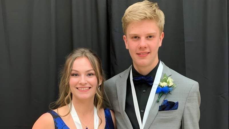 Ein formell gekleidetes Paar steht vor einem dunklen Vorhang auf dem Campus der Roncalli Central High.