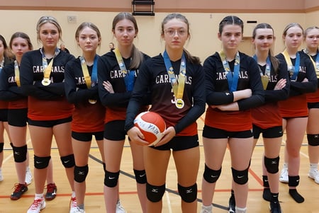 Eine Gruppe weiblicher Volleyballspielerinnen steht gemeinsam in der Turnhalle von Roncalli Central High.