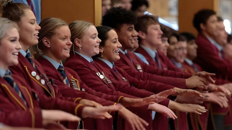 Eine Gruppe von Schülern in roten Talaren nimmt an einer formellen Zeremonie im Roncalli College teil.
