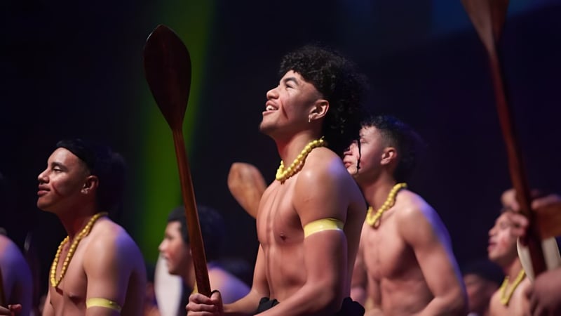 Schüler des Rongotai College führen eine traditionelle Tanzperformance mit paddeln und gelben Accessoires auf einer Bühne auf.