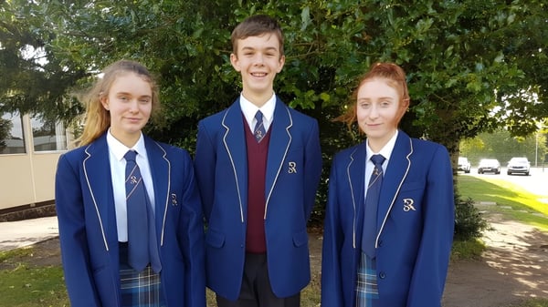 Drei Schüler in Schuluniformen stehen draußen vor einer grünen Wiese auf dem Gelände der Rookwood School.