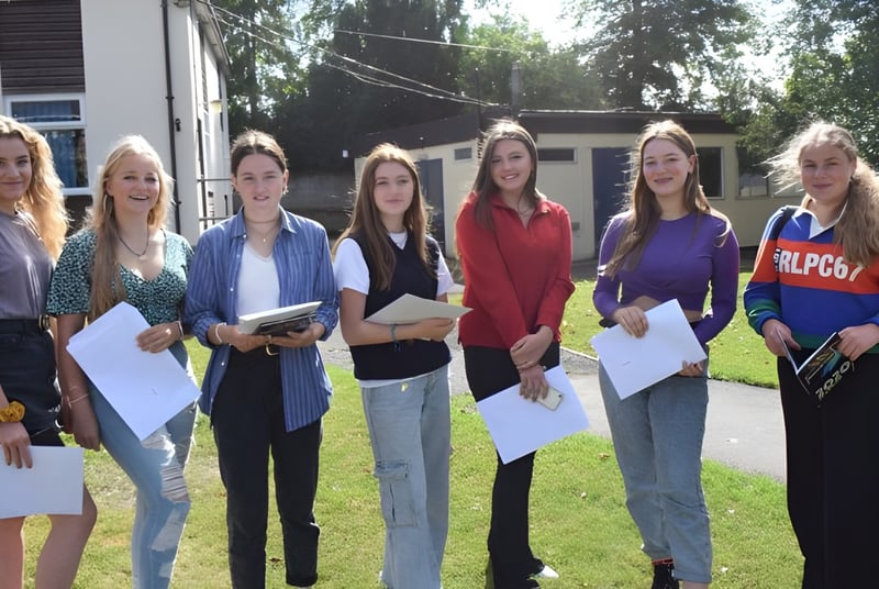 Eine Gruppe Schülerinnen der Rookwood School steht im Freien vor einem Gebäude und hält Papiere in den Händen.