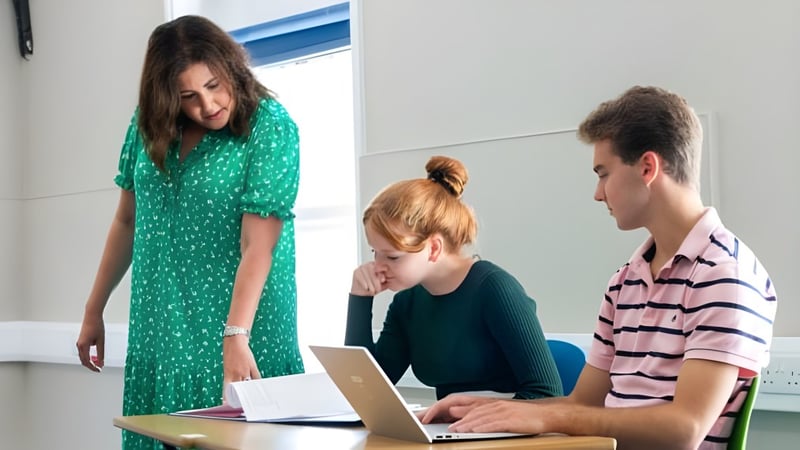 Drei Schüler der Rookwood School sitzen zusammen in einem Klassenraum und nutzen einen Laptop.