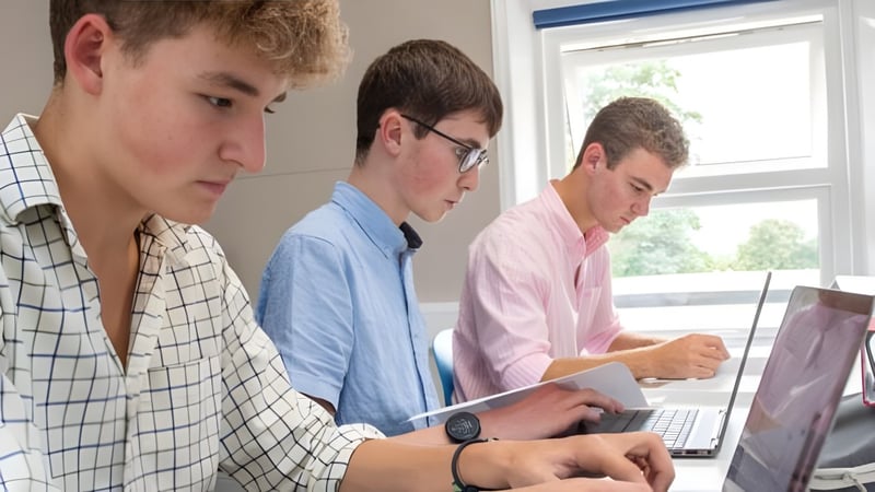 Drei Schülerinnen und Schüler der Rookwood School arbeiten konzentriert mit Laptops in einem hellen Raum.