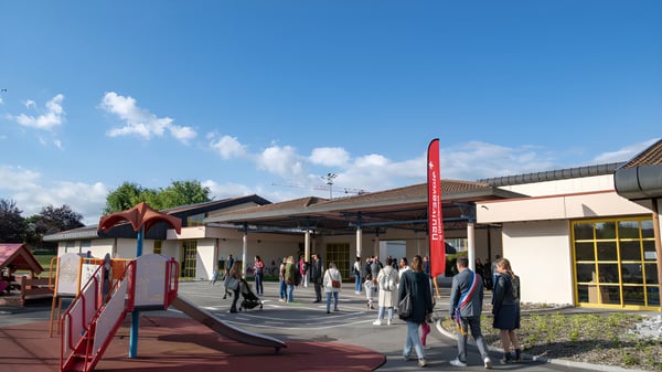 Eine Gruppe Schüler steht vor dem Gebäude der Rose-Des-Vents School im Außenbereich unter blauem Himmel.