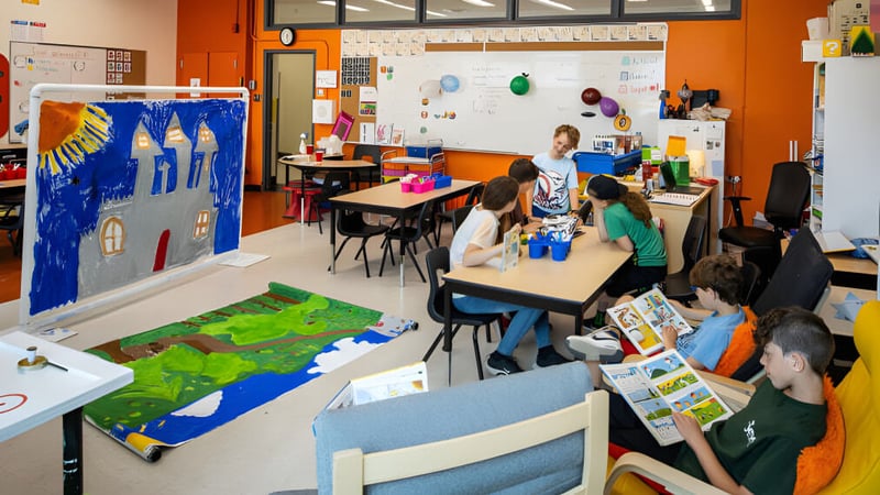 Schüler der Rose-Des-Vents School beteiligen sich aktiv am Kunstunterricht in einem farbenfrohen Klassenraum mit vielen Lernmaterialien.