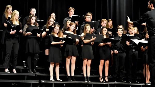 Schülerinnen und Schüler der Rosemount High School singen gemeinsam auf einer Bühne.