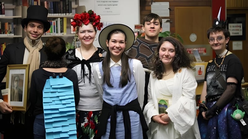 Eine Gruppe von Schülerinnen und Schülern steht in der Bibliothek des Rosny College vor Bücherregalen.
