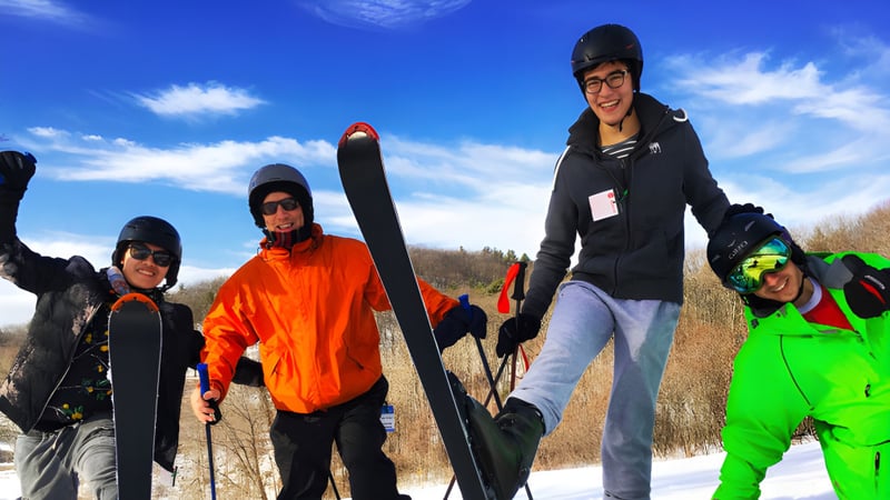 Eine Gruppe von Schülern der Ross School steht bei klarem Himmel auf einem schneebedeckten Feld in Winterkleidung.