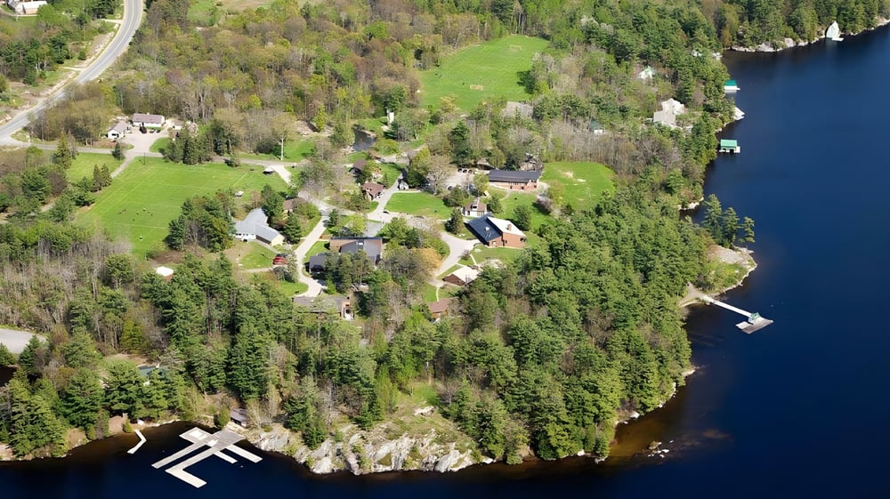 Eine bewaldete Landschaft mit einem gewundenen Weg und einem See im Hintergrund nahe Rosseau Lake College.