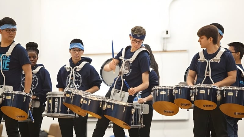 Schüler der Ross Sheppard High School üben gemeinsam mit Percussion-Instrumenten in einem hellen Innenraum.
