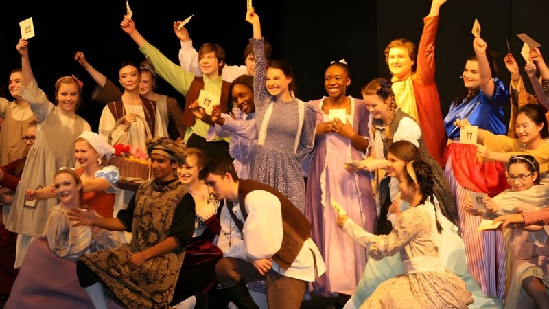 Eine Gruppe von Schülerinnen der Rothesay Netherwood School feiert in farbenfrohen Kostümen mit erhobenen Armen.