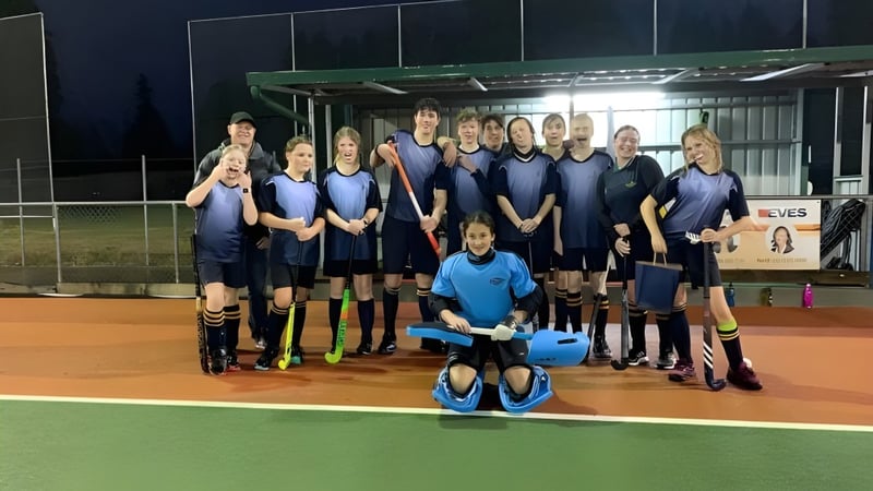 Eine Gruppe junger Hockeyspielerinnen der Rotorua Lakes High School posiert nachts auf dem Kunstrasenfeld.