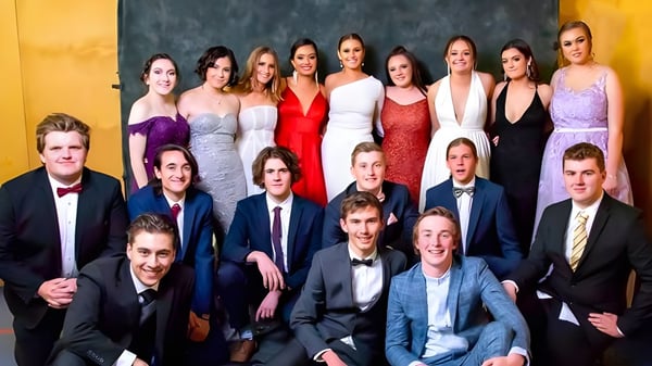 Eine Gruppe von formal gekleideten Schülerinnen und Schülern posiert vor einem gelben Hintergrund auf dem Campus der Roxby Downs Area School.