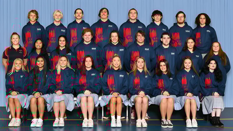 Eine Gruppe von Schülerinnen in einheitlichen Uniformen posiert vor einer blauen Wand auf dem Campus der Roxby Downs Area School.